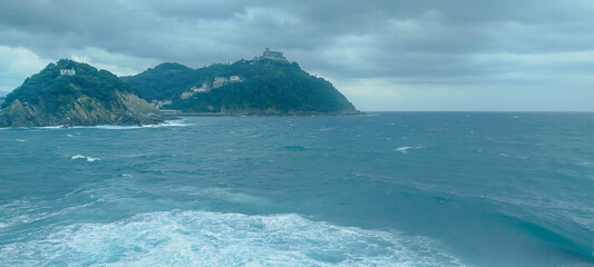 Fototapeta premium Vista panorámica de la bahía y la costa marítima bajo cielo nublado en San Sebastián, España.
