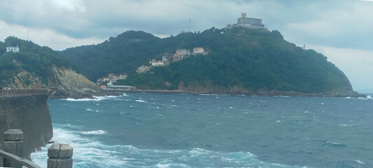 Fototapeta premium Vista panorámica de la bahía y la costa marítima bajo cielo nublado en San Sebastián, España.