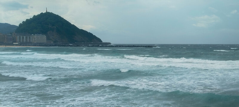 Monte verde junto al mar embravecido con olas blancas