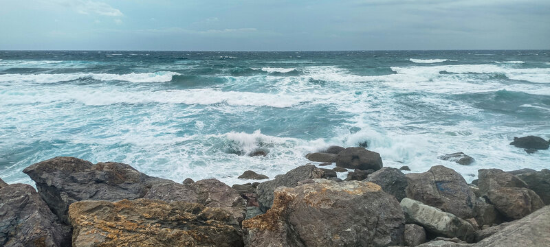 Olas rompiendo contra rocas en la costa marina bajo nubes