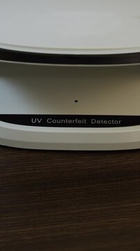 Examination of Thai baht (THB) cash money with UV counterfeit detector. Concept of authenticity check, fight against counterfeiting of banknotes, anti fraud measures in Thailand. Close up view.