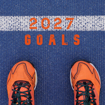 2027 goals. Orange running shoes located on the starting line of a blue track.