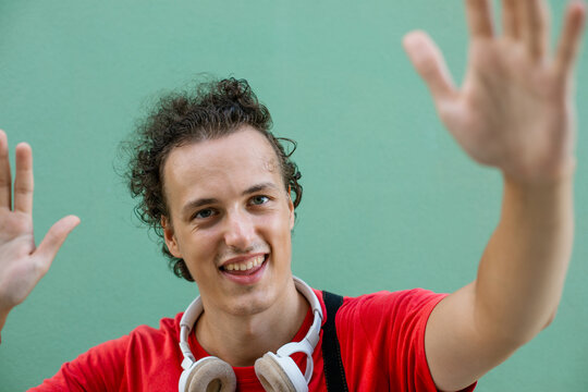 Happy young man waving at camera with friendly smile