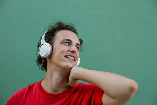 Thoughtful young man looking up while wearing wireless headphones