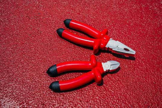 Insulated Red Combination Pliers and Side Cutters Hand Tools on Red Surface