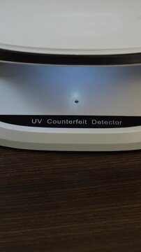 Examination of Sri Lanka rupee (LKR) cash money with UV counterfeit detector. Concept of authenticity check, fight against counterfeiting of banknotes, anti fraud measures in Sri Lanka. Close up view.