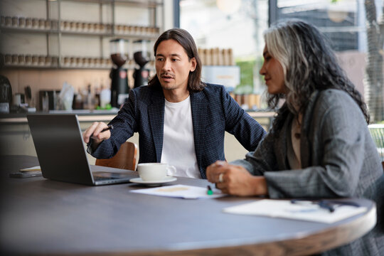 Business meeting at a cafe with laptop and coffee.