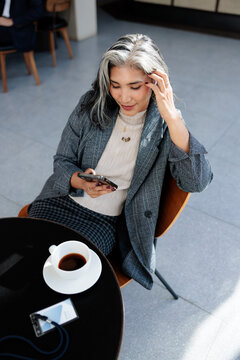 Woman with phone, coffee, and name tag.