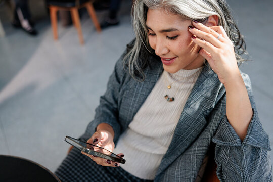 Woman with gray hair looks at her mobile phone thoughtfully.