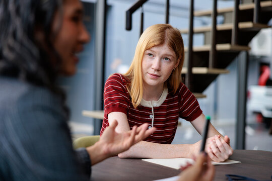 Two people in a meeting, one listening intently.