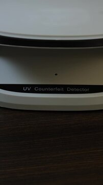 Examination of Uzbekistan Sum (UZS) cash money with UV counterfeit detector. Concept of authenticity check, fight against counterfeiting of banknotes, anti fraud measures in Uzbekistan. Close up view.