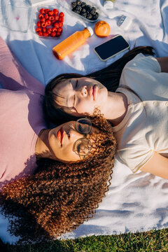 Two women lie on a blanket during a picnic