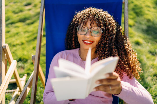 A woman reads a book sitting outdoors