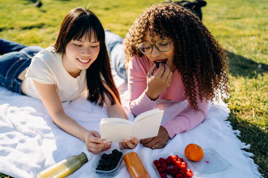 Two women lie on a blanket during a picnic