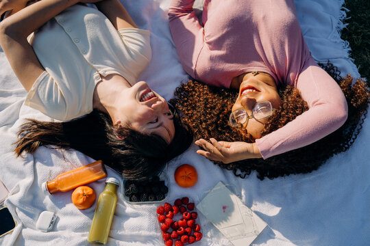 Two women lie on a blanket during a picnic