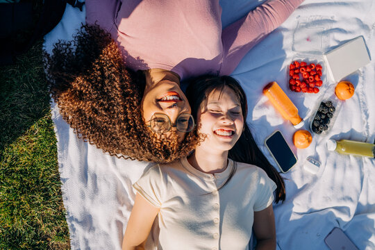 Two women lie on a blanket during a picnic