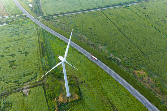  single wind turbine over green farmland beside rural road