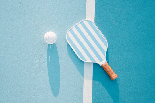Pickleball Paddle and Ball on Blue Court