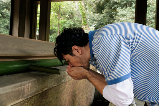 Man Purifying at Japanese Shrine Fountain
