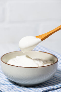 thick greek yogurt in a bowl and a spoon with yogurt, vertical