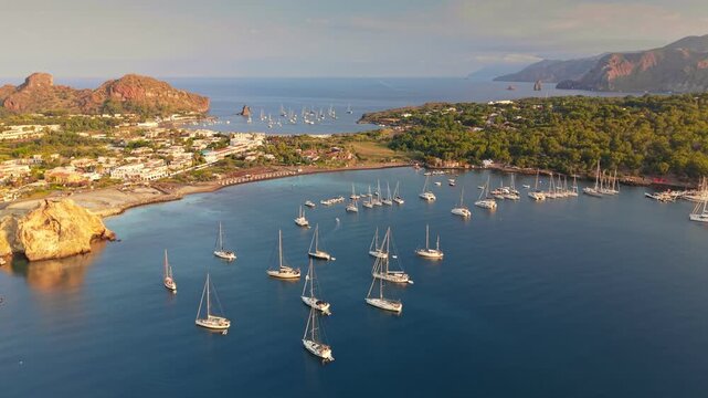 Aerial view of sailing yachts anchored in scenic bay of Vulcano island. Sailboats moored near coast in Aeolian islands. Vacation and yachting in the Mediterranean Sea, Sicily, Italy