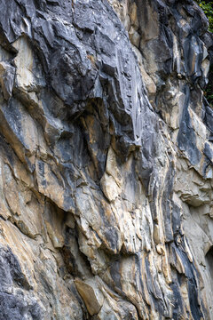 Paroi rocheuse escarp&eacute;e en calcaire stri&eacute; avec v&eacute;g&eacute;tation alpine &agrave; la base, g&eacute;ologie et texture de roche naturelle.