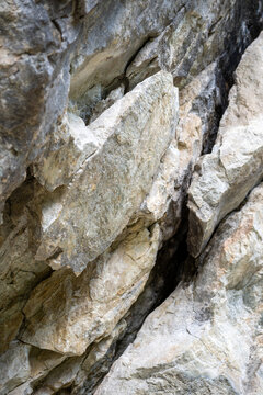Paroi rocheuse escarp&eacute;e en calcaire stri&eacute; avec v&eacute;g&eacute;tation alpine &agrave; la base, g&eacute;ologie et texture de roche naturelle.