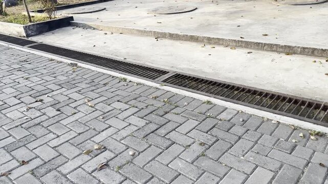Metal drainage grate on urban interlocking concrete paving street