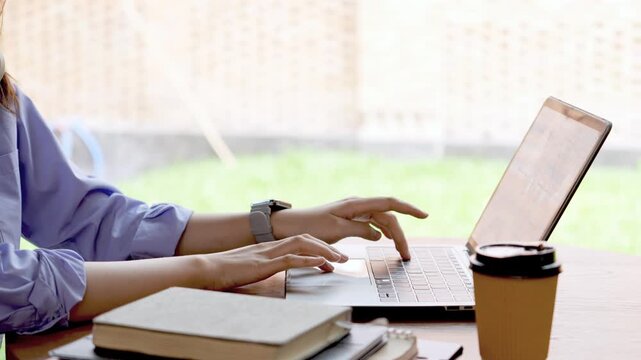 Young Asian Businesswoman Working Remotely with Laptop and Smartphone in Traditional Wooden Cafe, Digital Nomad Lifestyle