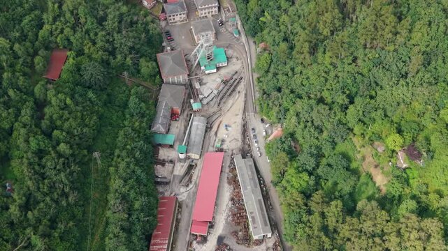Aerial view of Pozo Nicolasa coal mine complex with pithead headframe, narrow gauge rail tracks and industrial storage yards in valley near Mieres, Asturias, Spain