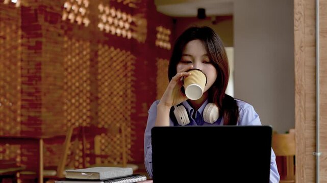 Young Asian Businesswoman Working Remotely with Laptop and Smartphone in Traditional Wooden Cafe, Digital Nomad Lifestyle