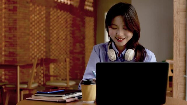 Young Asian Businesswoman Working Remotely with Laptop and Smartphone in Traditional Wooden Cafe, Digital Nomad Lifestyle