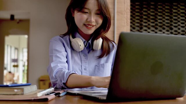 Young Asian Businesswoman Working Remotely with Laptop and Smartphone in Traditional Wooden Cafe, Digital Nomad Lifestyle