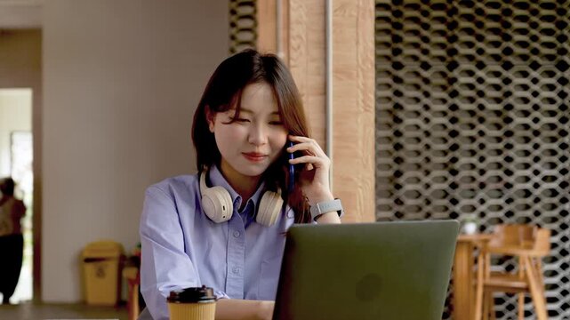 Young Asian Businesswoman Working Remotely with Laptop and Smartphone in Traditional Wooden Cafe, Digital Nomad Lifestyle