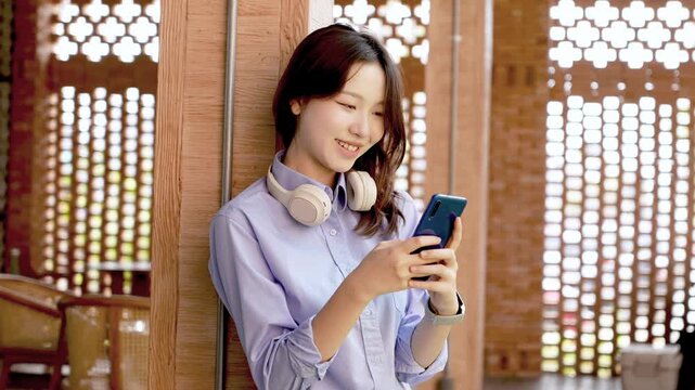 Young Asian Businesswoman Working Remotely with Laptop and Smartphone in Traditional Wooden Cafe, Digital Nomad Lifestyle