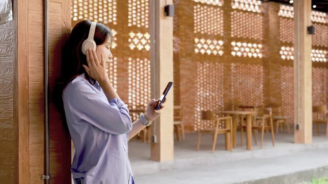Young Asian Businesswoman Working Remotely with Laptop and Smartphone in Traditional Wooden Cafe, Digital Nomad Lifestyle