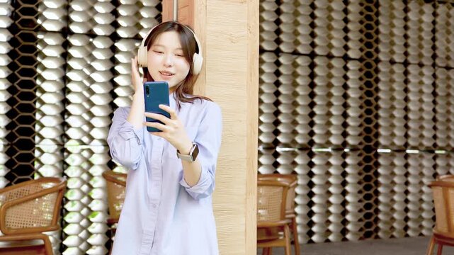 Young Asian Businesswoman Working Remotely with Laptop and Smartphone in Traditional Wooden Cafe, Digital Nomad Lifestyle