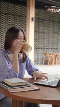 Young Asian Businesswoman Working Remotely with Laptop and Smartphone in Traditional Wooden Cafe, Digital Nomad Lifestyle
