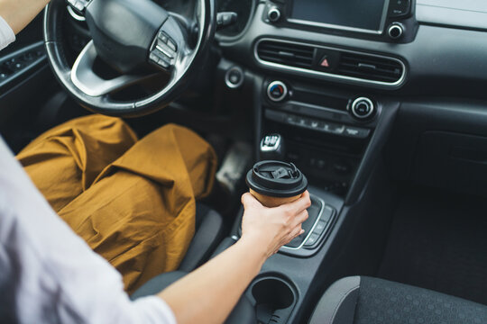Woman hand hold a takeaway coffee cup while driving during her morning commute
