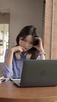 Young Asian Businesswoman Working Remotely with Laptop and Smartphone in Traditional Wooden Cafe, Digital Nomad Lifestyle
