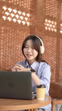 Young Asian Businesswoman Working Remotely with Laptop and Smartphone in Traditional Wooden Cafe, Digital Nomad Lifestyle