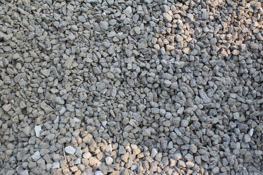 Pile of crushed stones with sunlight reflection. Top view. Crushed stone is commonly used as a mixture for concrete, road bases, or building foundation layers. Top view.
