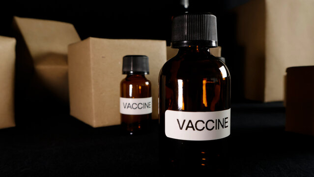 Vaccine bottles with labels showing VACCINE presented on a dark background, illustrating pharmaceutical packaging, global distribution, and healthcare supply chain concepts