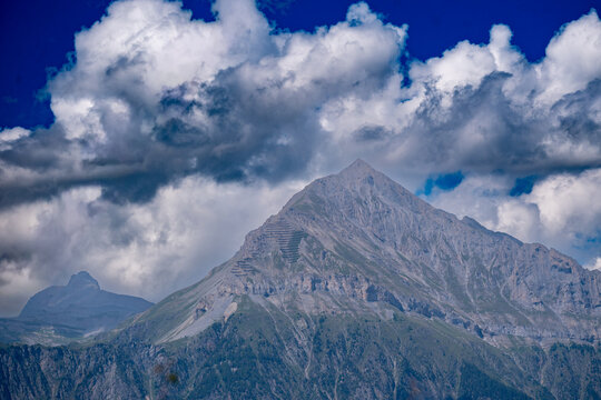 Le Chavalard, sommet montagneux majestueux sous un ciel nuageux dramatique
Vue panoramique d'une montagne rocheuse imposante se d&eacute;tachant sur un ciel bleu azur rempli de nuages cumulus denses et dram