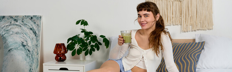 Naklejka premium Young woman enjoys matcha in cozy room, embracing a healthy lifestyle