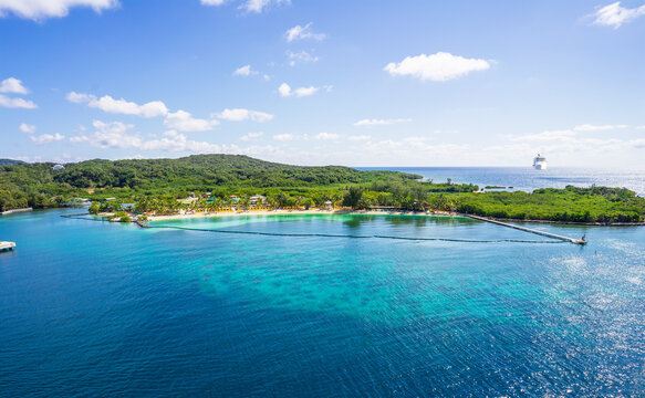View of Mahogany Bay beach with ship sailing to port. 