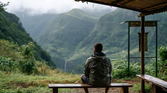 A dynamic, desaturated documentary style photography of urban exploration. An over-the-shoulder wide shot of a traveler discovering a breathtaking view of a lush, misty mountain ra