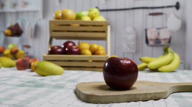 Red apple on cutting board with display filled with fruit behind it