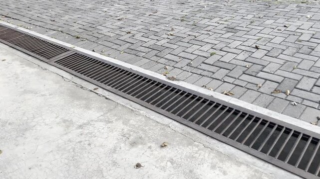 Long Metal Drainage Grate on Paving Block Sidewalk Wide Shot