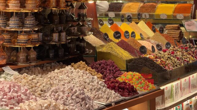 Close-up shot of an ornate spice stall displaying colorful pyramids of spices, dried tea, and traditional Turkish delight at the historic Grand Bazaar in Istanbul, Turkey.